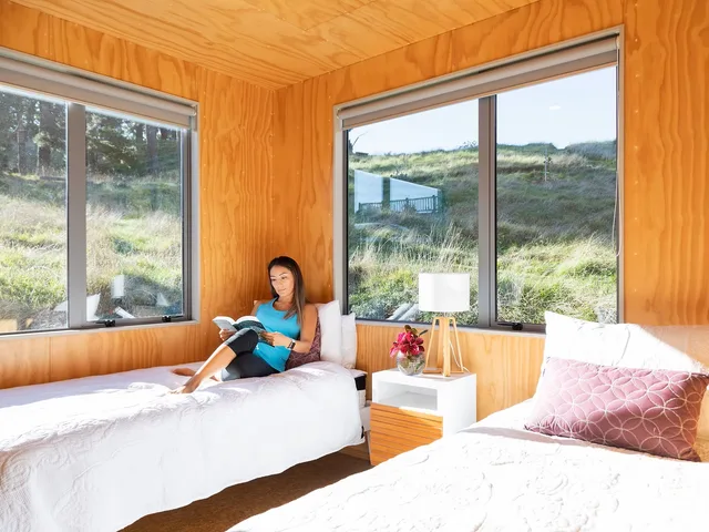 Sunlit timber-lined accommodation room with twin beds
