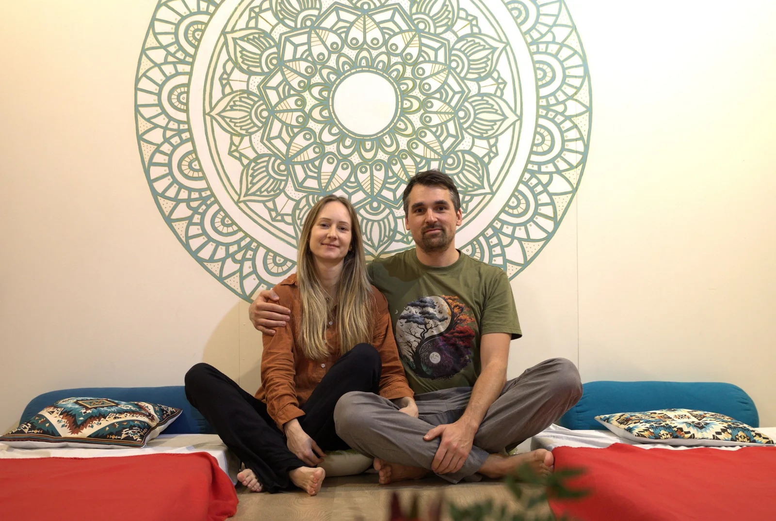 Two people seated together in front of a large circular wall design